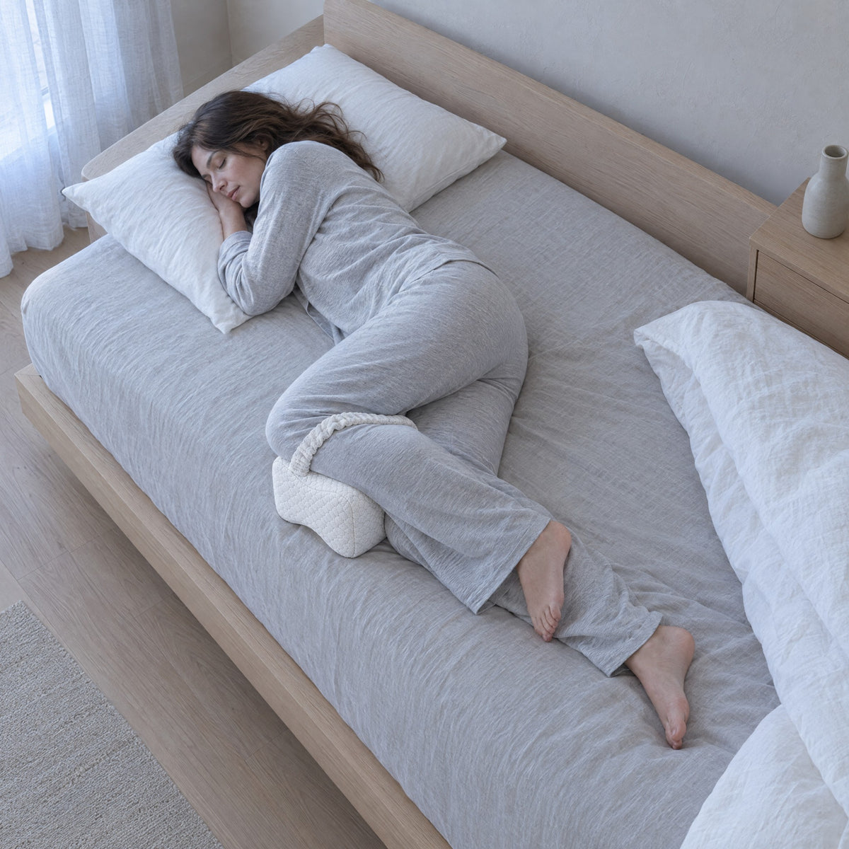 Femme endormie sur le côté avec le coussin de jambes GENOU blanc aux genoux