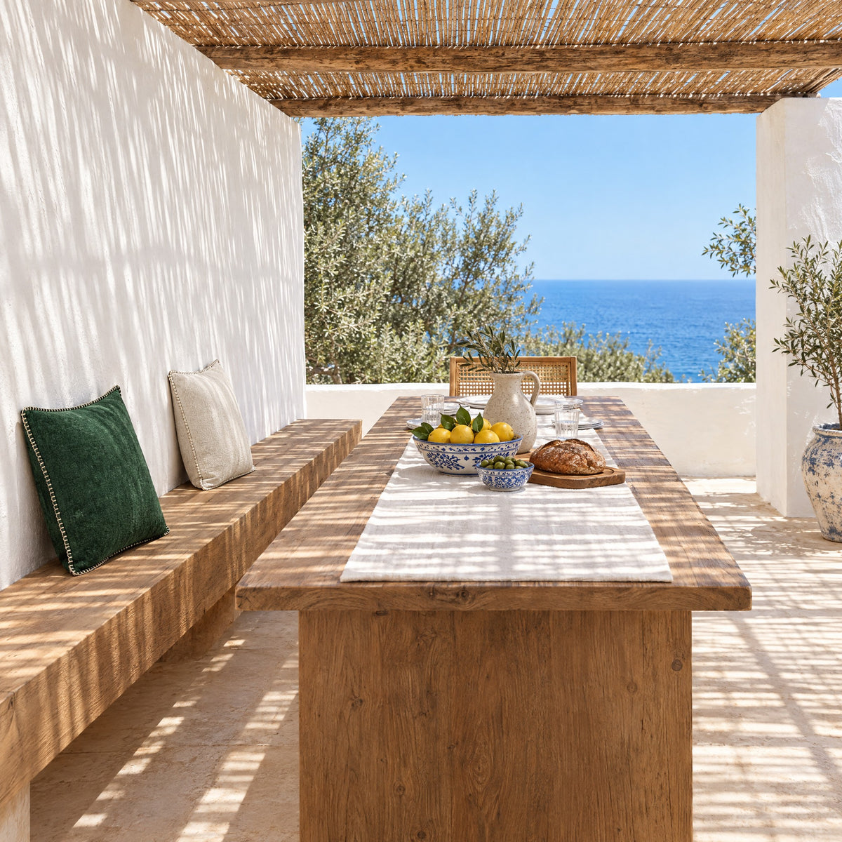 Banc garni de coussins GALON vert forêt et ivoire le long d'une table sous une pergola