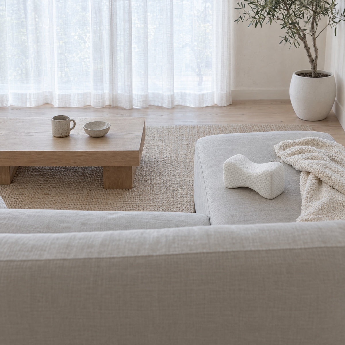 Coussin de jambes GENOU blanc sur la méridienne d'un canapé en lin