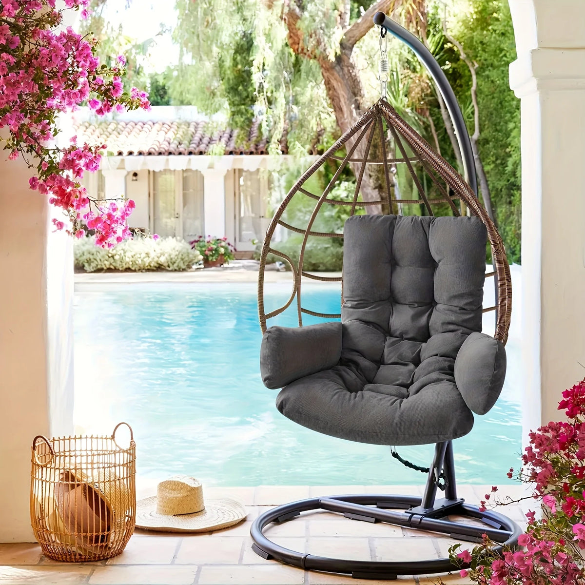 OEUF — Coussin gris foncé dans un fauteuil suspendu sur une terrasse au bord d'une piscine