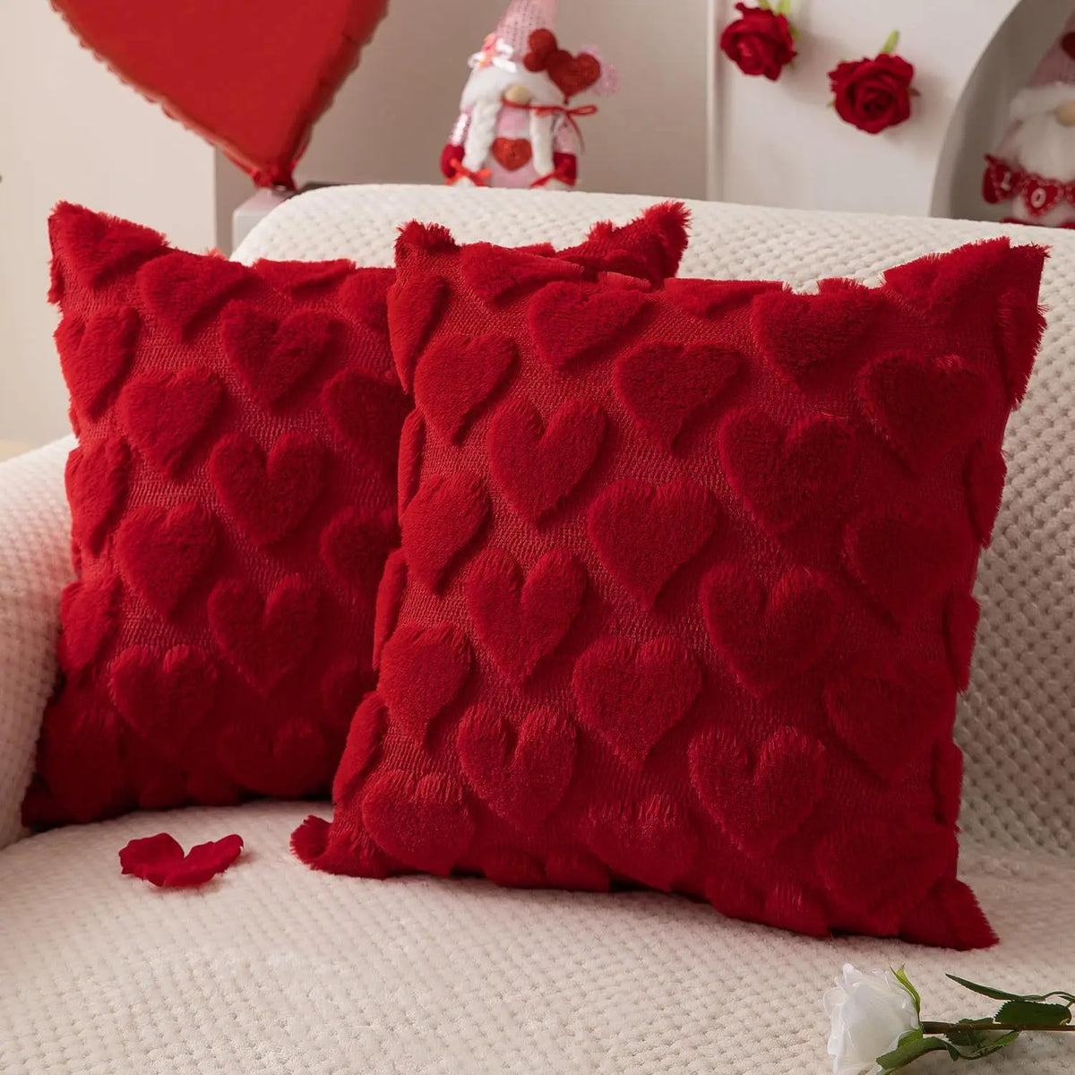 HOUX — Deux housses de coussin rouges à cœurs en relief sur un canapé