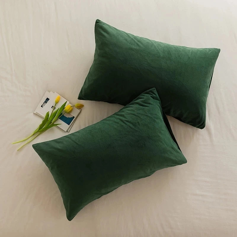 CARMIN — Deux housses de coussin rectangulaires en velours vert sapin posées sur un lit