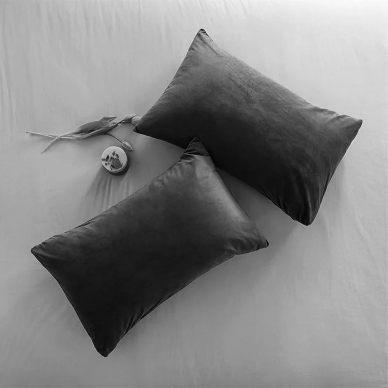 CARMIN — Deux housses de coussin rectangulaires en velours gris foncé posées sur un lit