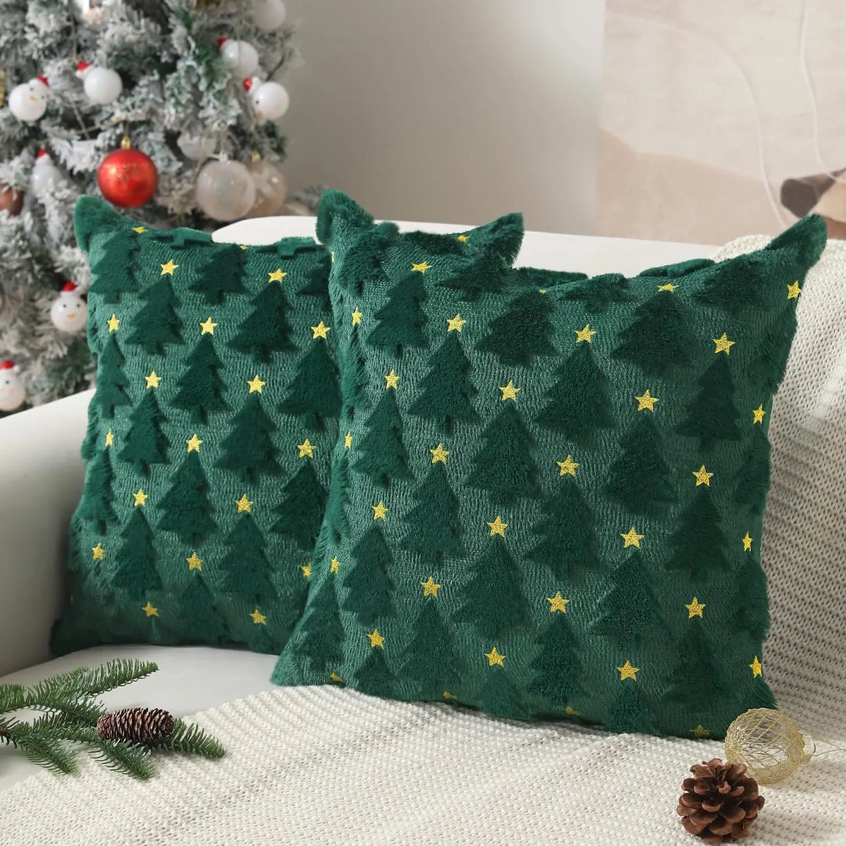 HOUX — Deux housses de coussin de Noël vertes à sapins en relief et étoiles dorées sur un canapé