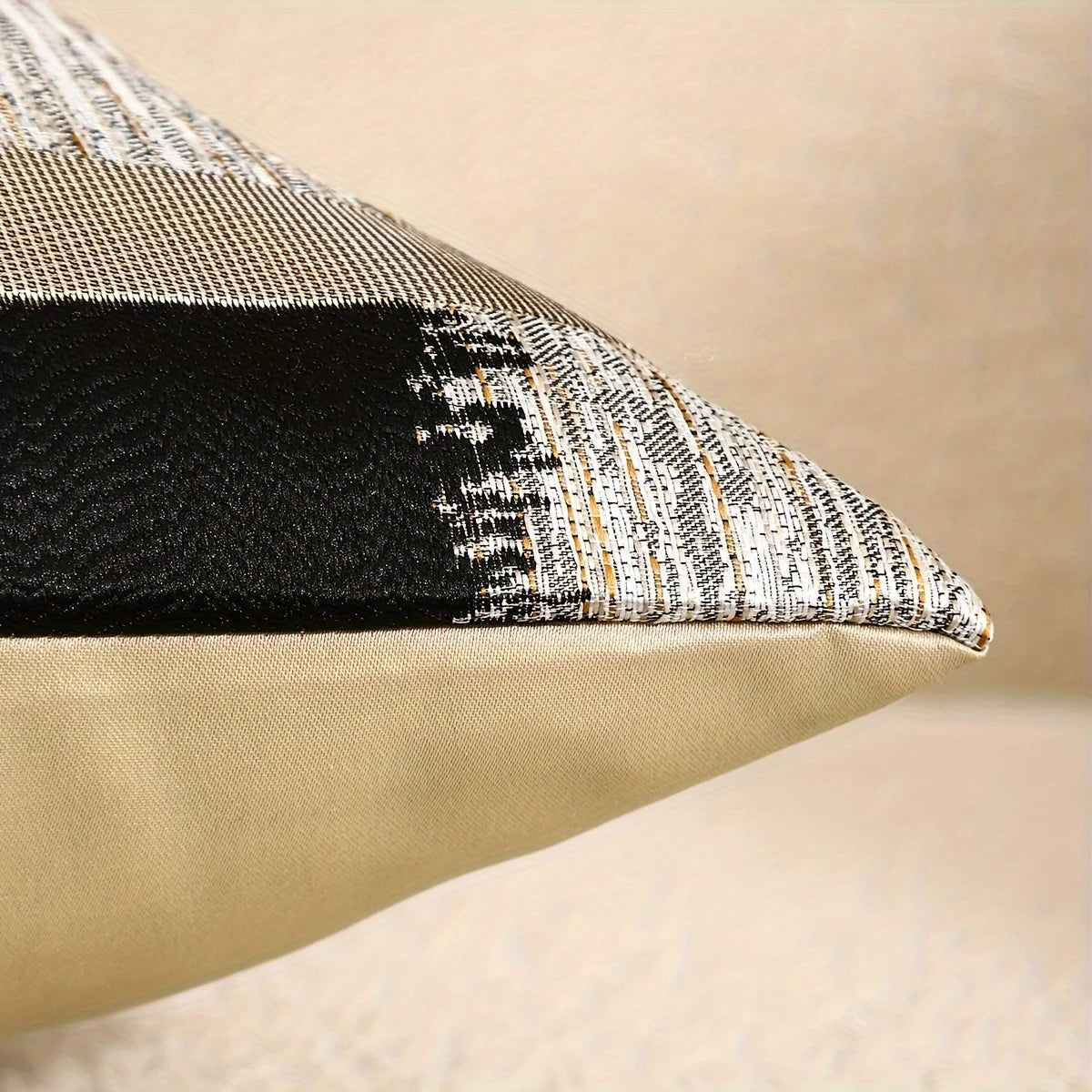 OPERA — Coin d'une housse de coussin jacquard noir et or, dos uni doré