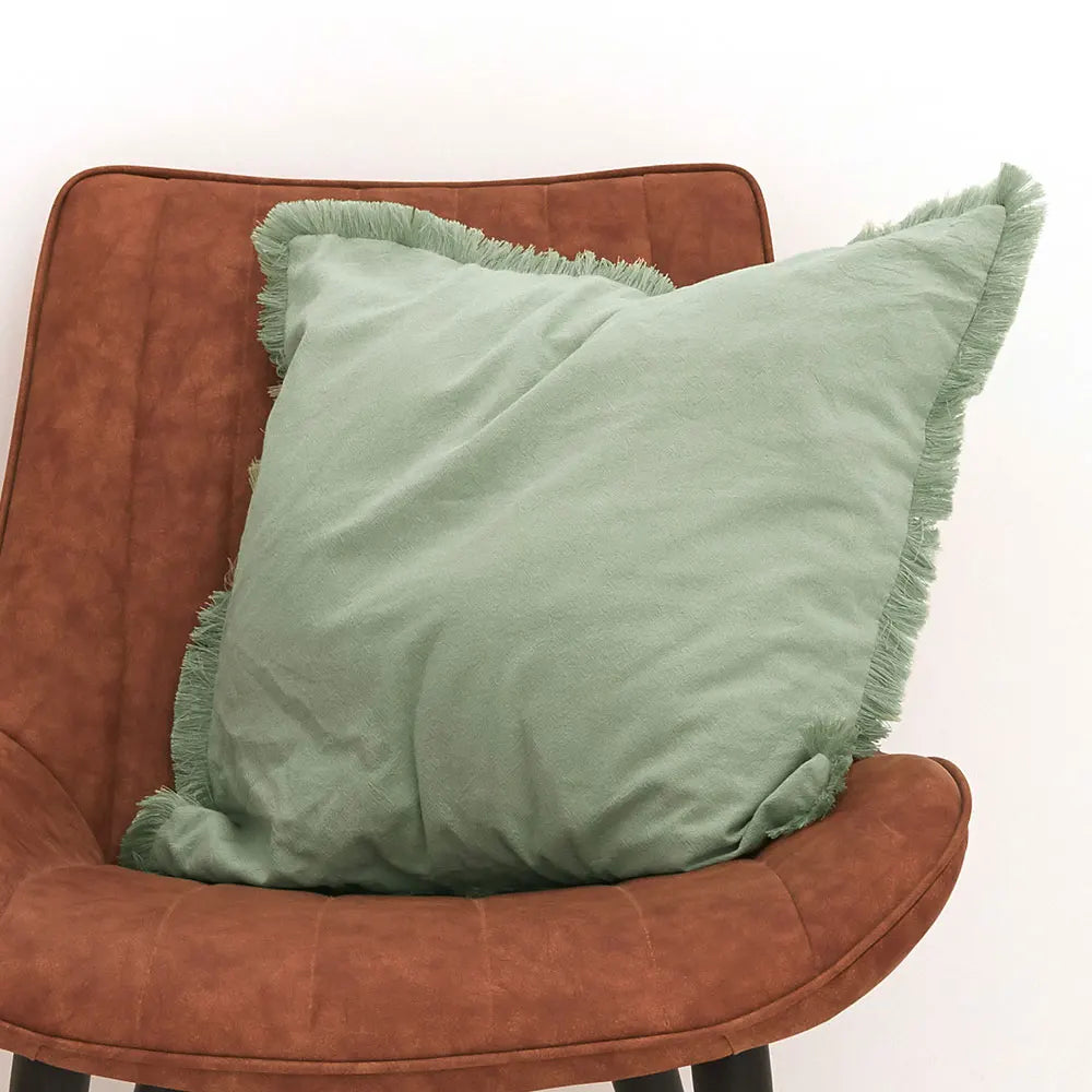 FRANGE — Housse de coussin à franges, coloris Vert clair, posée sur une chaise