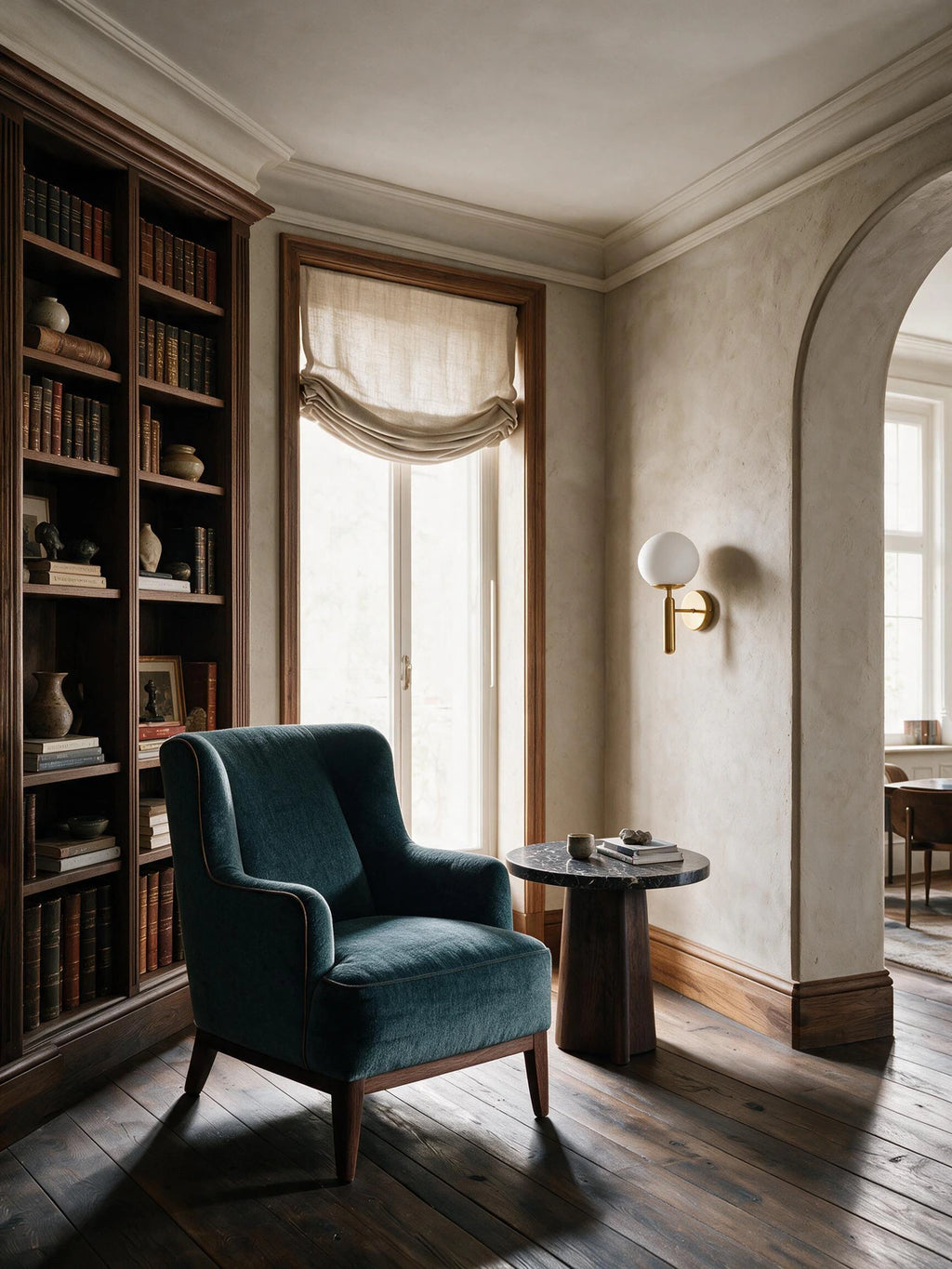 Applique murale SOLIS en métal — applique dorée dans une bibliothèque avec fauteuil bleu — Maison Beaurel