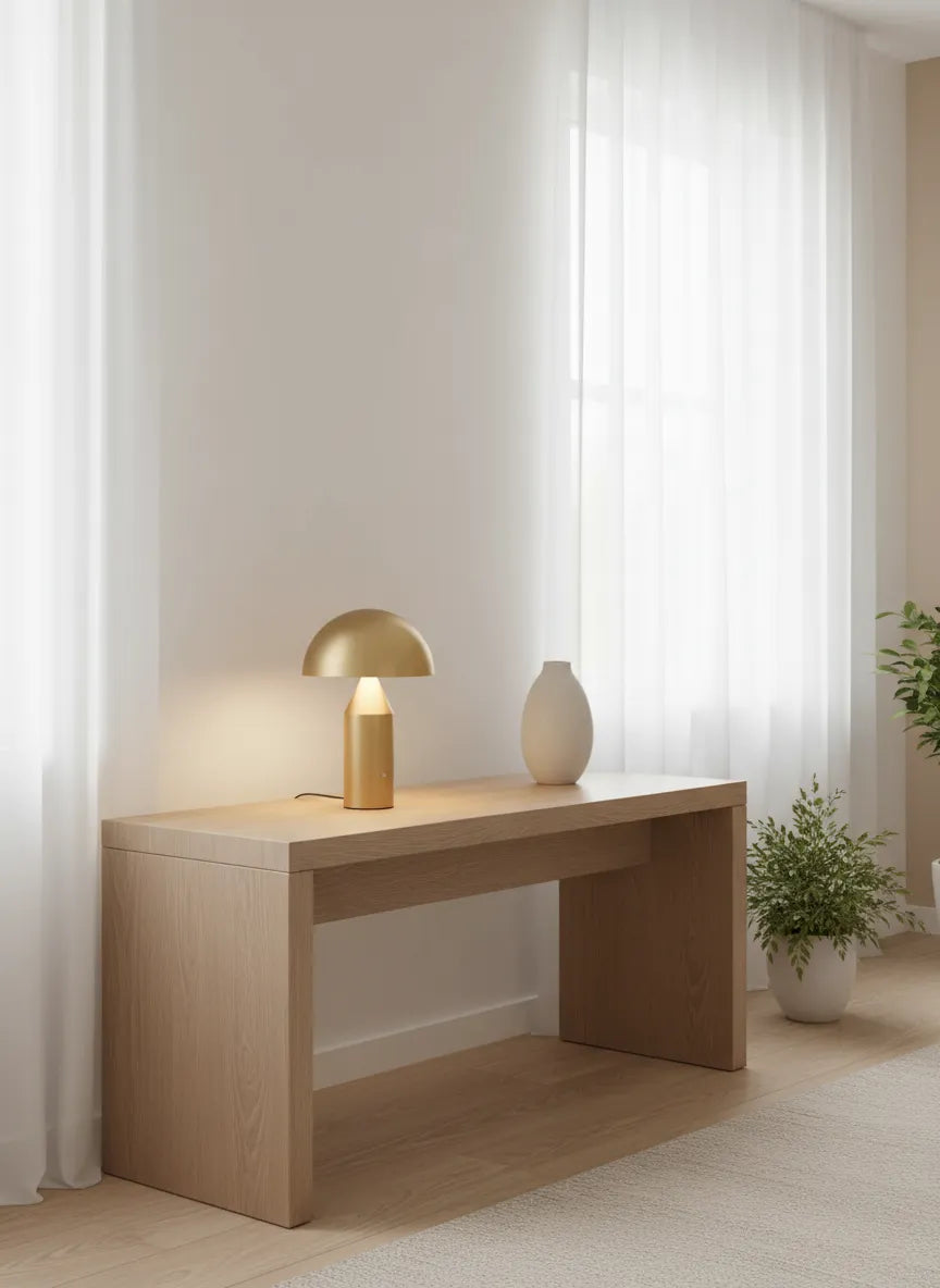 CÈPE — Lampe dorée allumée sur une console en bois clair, ambiance cocon