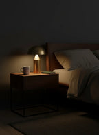 CÈPE — Lampe dorée allumée sur une table de chevet, ambiance nuit