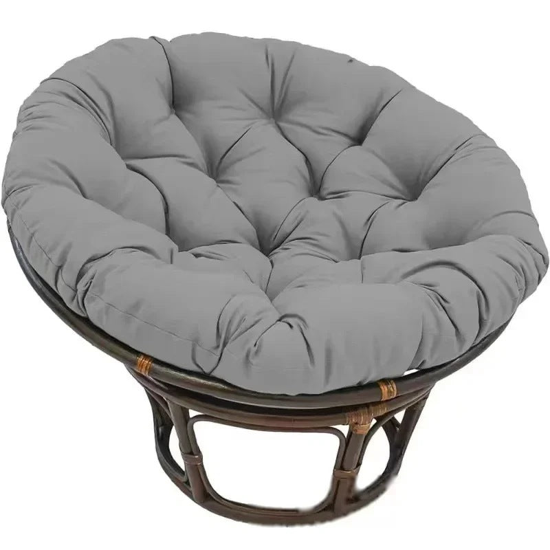 PAPASAN — Coussin rond capitonné coloris Gris foncé posé sur un fauteuil papasan en rotin