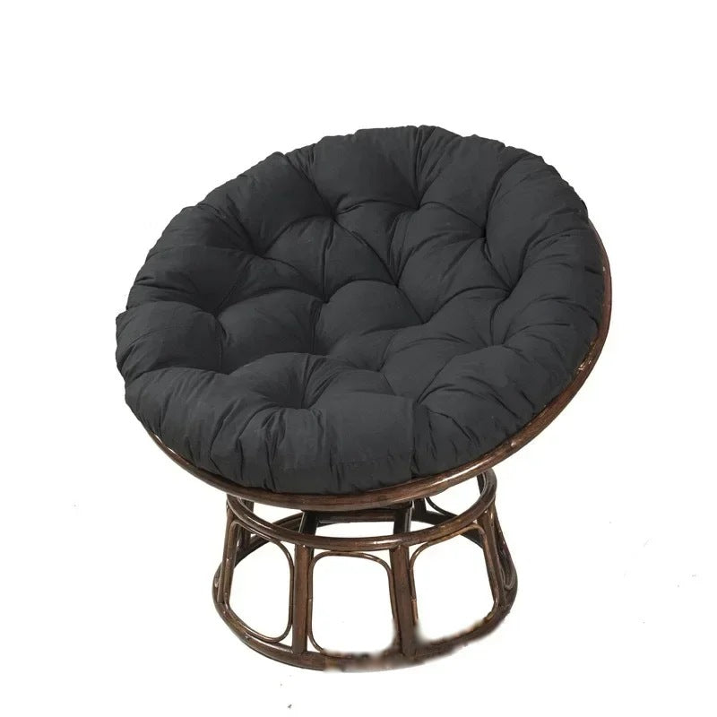 PAPASAN — Coussin rond capitonné coloris Noir posé sur un fauteuil papasan en rotin
