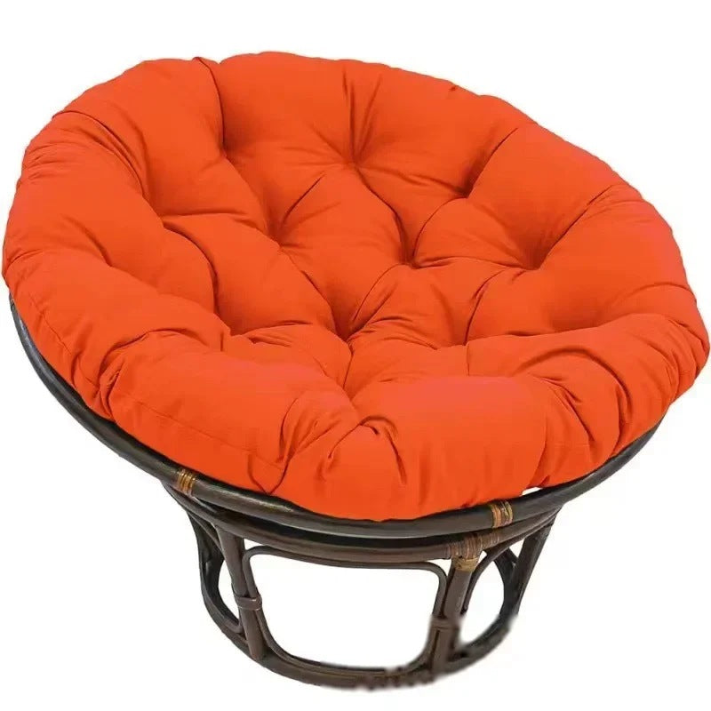 PAPASAN — Coussin rond capitonné coloris Orange posé sur un fauteuil papasan en rotin